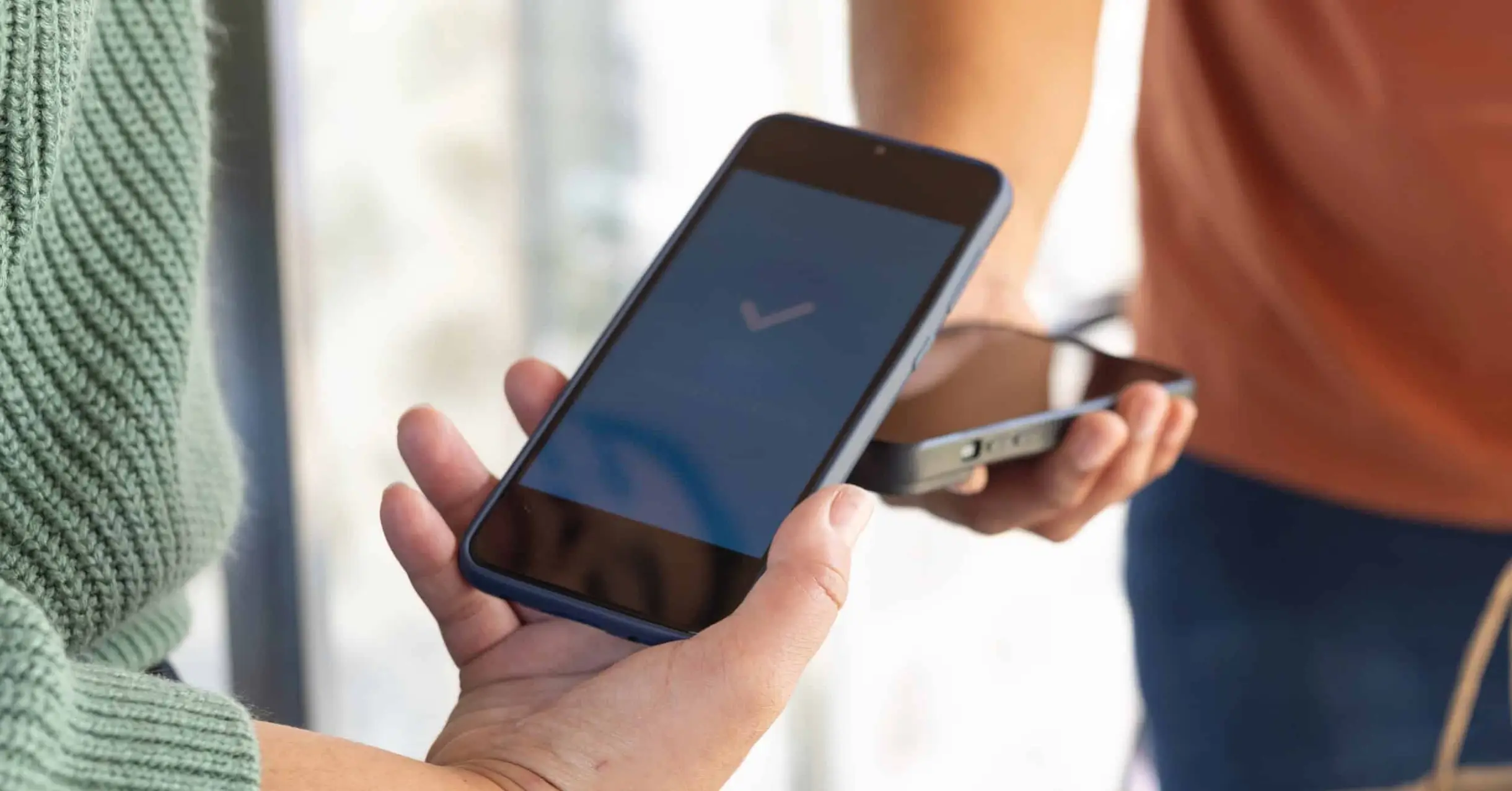 Une femme tend son mobile vers un TPE pour payer.