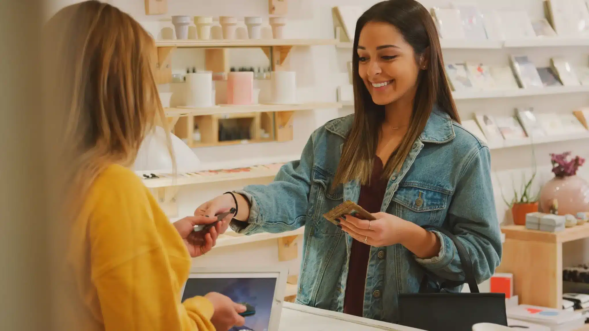 Une cliente payant une assistante commerciale à la caisse d'un magasin de cadeaux avec carte de débit